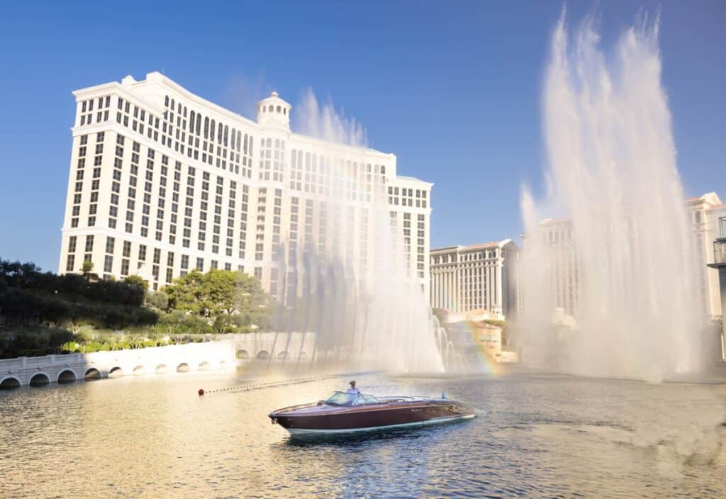 A classic wooden boat floats on the water in front of the Bellagio Hotel as fountains spray high into the air in Las Vegas.